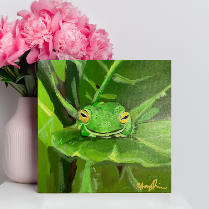 Green frog sleeping on green leaf, surrounded by more green leaves. 