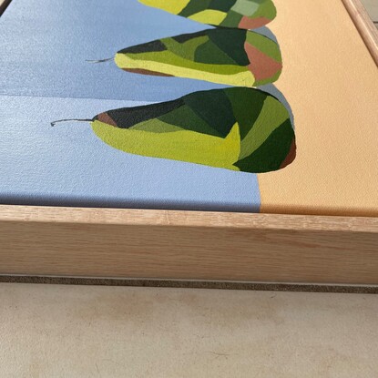 3 green pears in a row on a peachy coloured surface before a cool grey background.