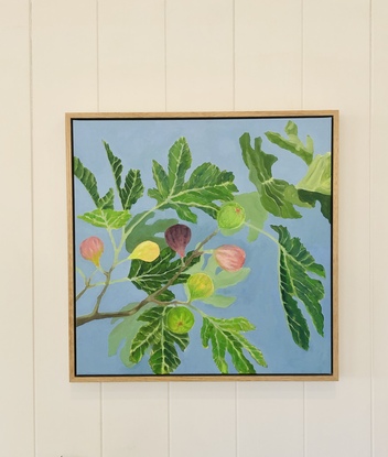 Green fig leaves and colourful figs on a branch with light blue background. 