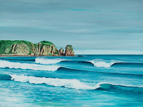 Clean blue waves and ocean wrapping around a green headland