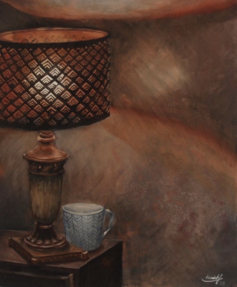 A retro copper lampshade sits atop a bedside drawer,  illuminated by a household table lamp. There is a coffee mug at the base of the lamp and the picture is flooded with soft, warm light.