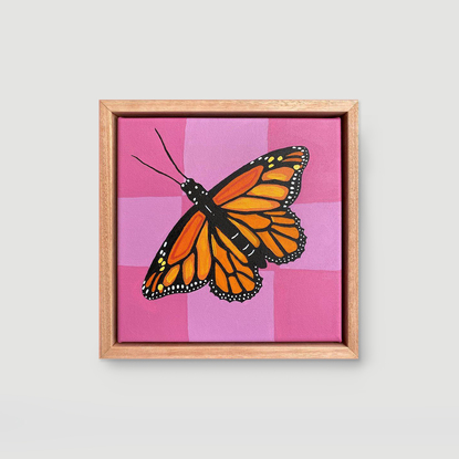 A Monarch Butterfly with a pink checkered background. Framed on Flooded Gum.