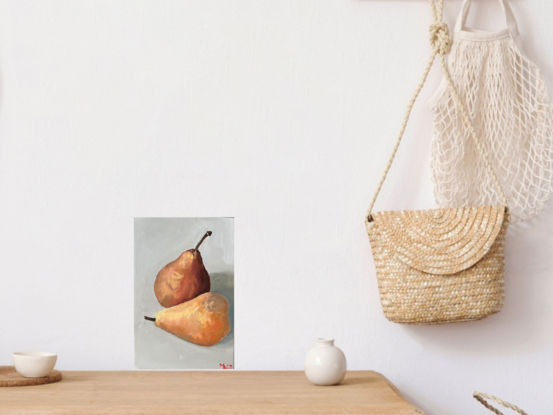 Two brown pears sitting next to each other on an off white background