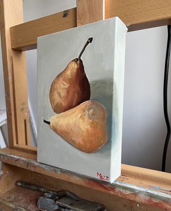 Two brown pears sitting next to each other on an off white background