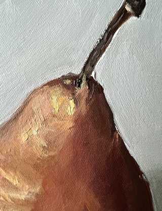 Two brown pears sitting next to each other on an off white background