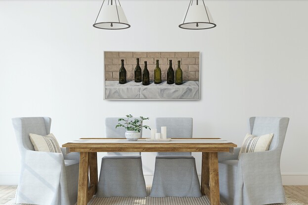 Six empty green wine bottles on a white tablecloth in front of a brick wall.