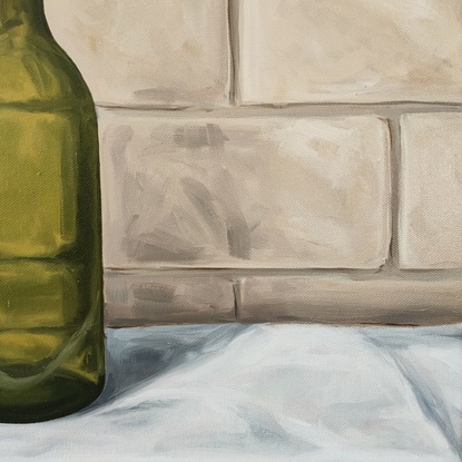 Six empty green wine bottles on a white tablecloth in front of a brick wall.