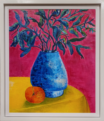 Blue pottery vase which contains branches and leaves from a plant. All sitting on a yellow table cloth with a orange. 