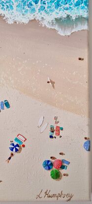 Surfers come and go from the ocean and sunbathers stretch out along the beach to enjoy the sun.