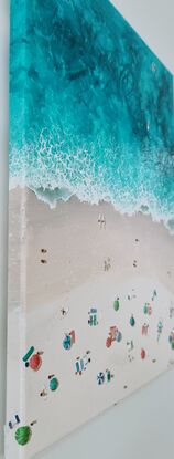 Surfers come and go from the ocean and sunbathers stretch out along the beach to enjoy the sun.