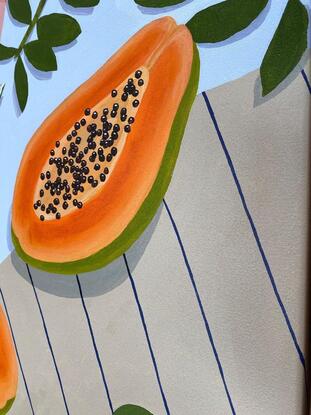 Papaya and limes on a blue table with apricot and brown tea towels. 