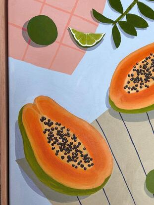 Papaya and limes on a blue table with apricot and brown tea towels. 