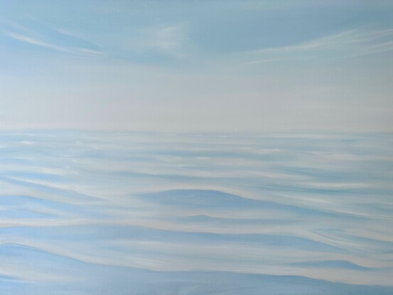 Barely there waves and ripples on ocean surface under blue and whtie sky