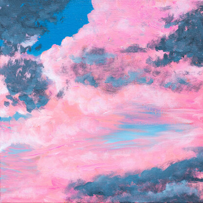 Fluffy pink and grey clouds float in front of a blue sky