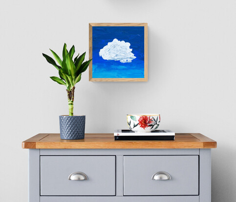 A lumpy textured white and grey blob shaped cloud floats in the centre of the canvas on a background of deep cobalt blue that has been applied with a palette knife.