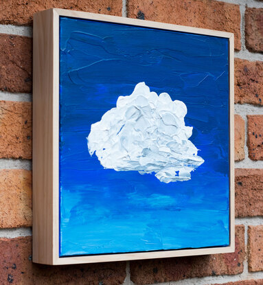 A lumpy textured white and grey blob shaped cloud floats in the centre of the canvas on a background of deep cobalt blue that has been applied with a palette knife.