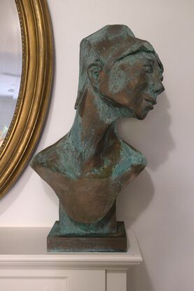 Bust of woman looking across left shoulder. Copper colour with aged blue patina. 