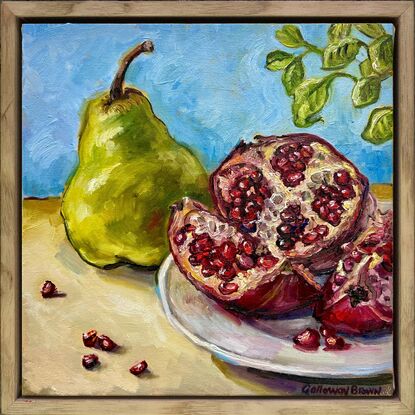 Still life setting with a green pear and cut pomegranate with seeds on a white plate