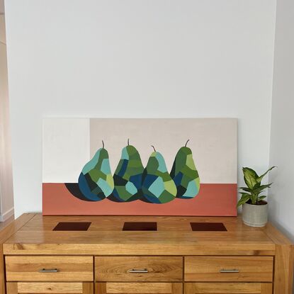 Four pears on a terracotta surface with a beige background. The pears are painted in a geometric style in warm greens and blues.