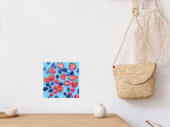 A square oil painting of blueberries, blackberries, raspberries and strawberries on a blue background. Some of the strawberries are sliced in half.