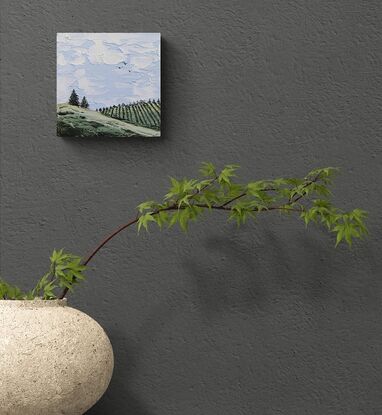 textured landscape of soft blue skies clouds and green rolling hills with vineyard