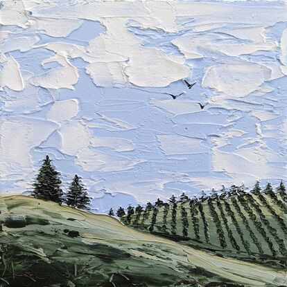 textured landscape of soft blue skies clouds and green rolling hills with vineyard