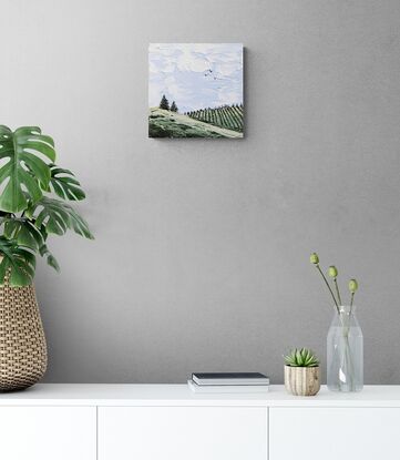 textured landscape of soft blue skies clouds and green rolling hills with vineyard