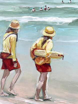 Bright and olourful red and yellow surf lifesavers on patrol watching people swimming in the surf. Cool green water with white waves. 