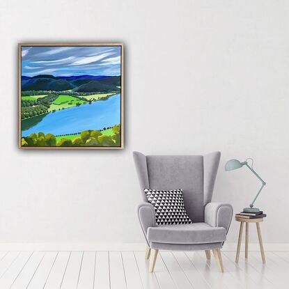 A view of the Hawkesbury River from Hawkins Lookout Point under a cloudy moody grey sky. There are trees in the foreground directly underneath the viewer and trees lining the river and dark blue and green hills and trees in the distance. 