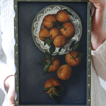 Painting of still life tangerines in a green patterned frame.