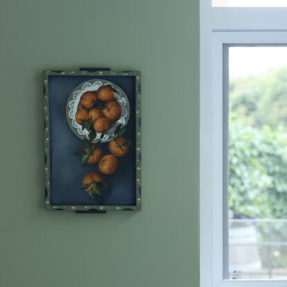 Painting of still life tangerines in a green patterned frame.