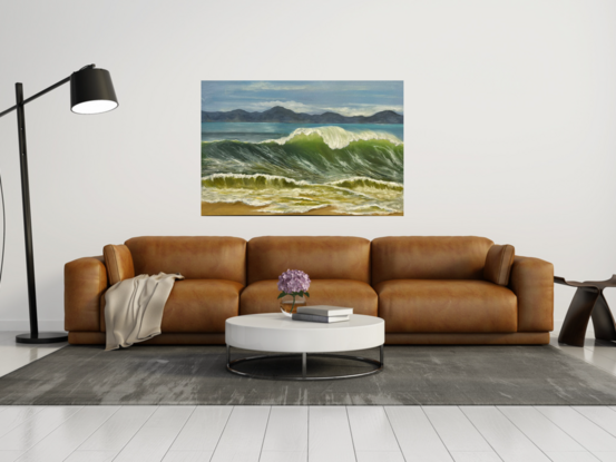 Large wave cresting on beach with mountains in background.