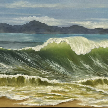 Large wave cresting on beach with mountains in background.