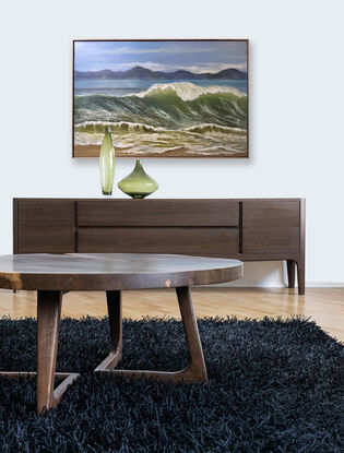 Large wave cresting on beach with mountains in background.