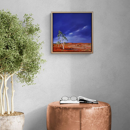 Australian landscape in yellows, oranges and deep blue sky with a road and gum trees, dust storm coming