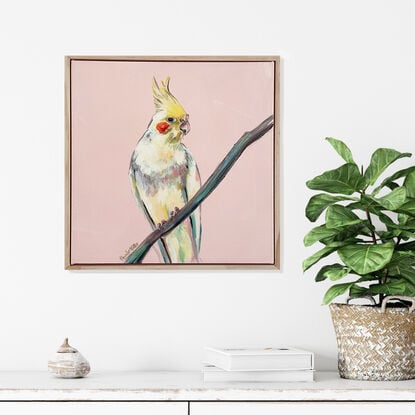 Yellow cockatiel portrait seated on a thin branch, with a retro peach background. Framed and ready to hang.