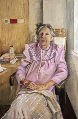 Old woman wearing a pink robe sitting on an armchair in a hospital room