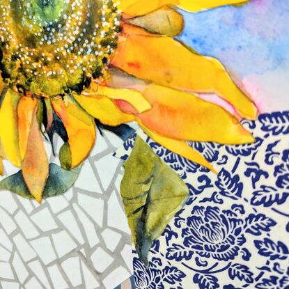 A single sunflower, facing towards the viewer, is created using watercolour. It sits in a blue and white detailed vase, on a blue and white tablecloth - both created using collaged paper. The background is a white, geometric, marble-like texture, also created in collaged paper. 