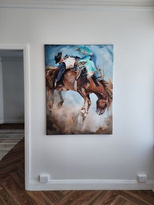 Close up of a cowboy in turquoise chaps riding a wild bucking horse in rodeo. Dust and fast action