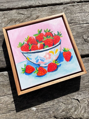 a textural bowl of strawberries with a pastel pink and blue background. 