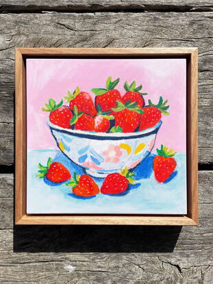 a textural bowl of strawberries with a pastel pink and blue background. 