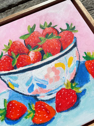 a textural bowl of strawberries with a pastel pink and blue background. 