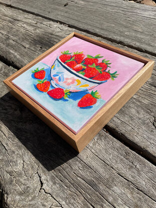 a textural bowl of strawberries with a pastel pink and blue background. 