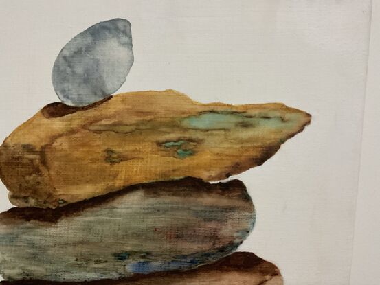 4 ocher and blue/grey rocks balancing on top of each other in a tower. 