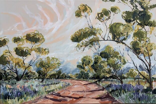 Spring grasses edge a red dirt track that weaves through mallee trees. A pink and blue sky have white whispering clouds. 