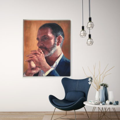 A strong portrait of a male with a beard with his head resting on his hands. He is deep in thought. It is framed in a white floating frame.