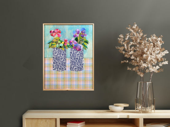 Two blue and white vases sit on a multicoloured checkered tablecloth. In the right vase sits purple flowers with gold centres, and the left are hot pink flowers with gold centres.