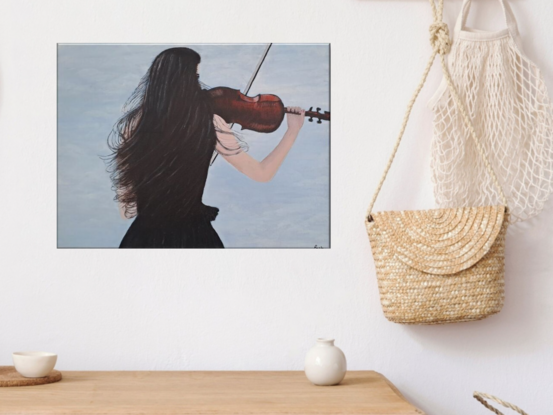 woman playing the violin against a light blue sky. Her back is to us, her long black hair flowing in the wind.