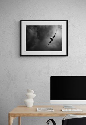 A black and white photograph of the Airbus A350, flying towards the photographer, in a steep right-hand turn in front of a dramatic cloudy background.