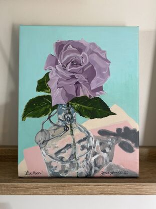 Single long stem purple rose in a glass water bottle, casting a shadow on a pink and teal background.